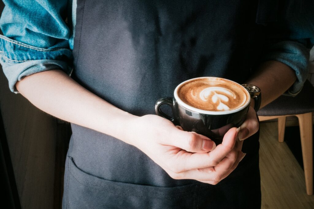 Mujer sosteniendo taza de cafe capuchino